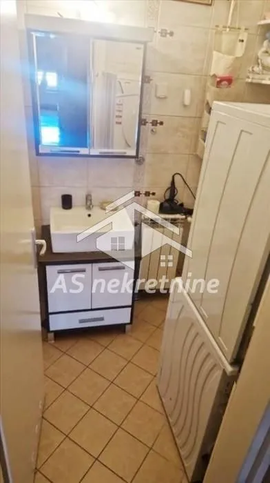 Smaller bathroom with a sink, mirror, and tiles.