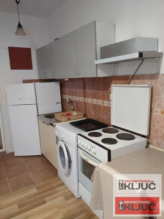 Manja kuhinja sa šporetom, frižiderom i elementima.