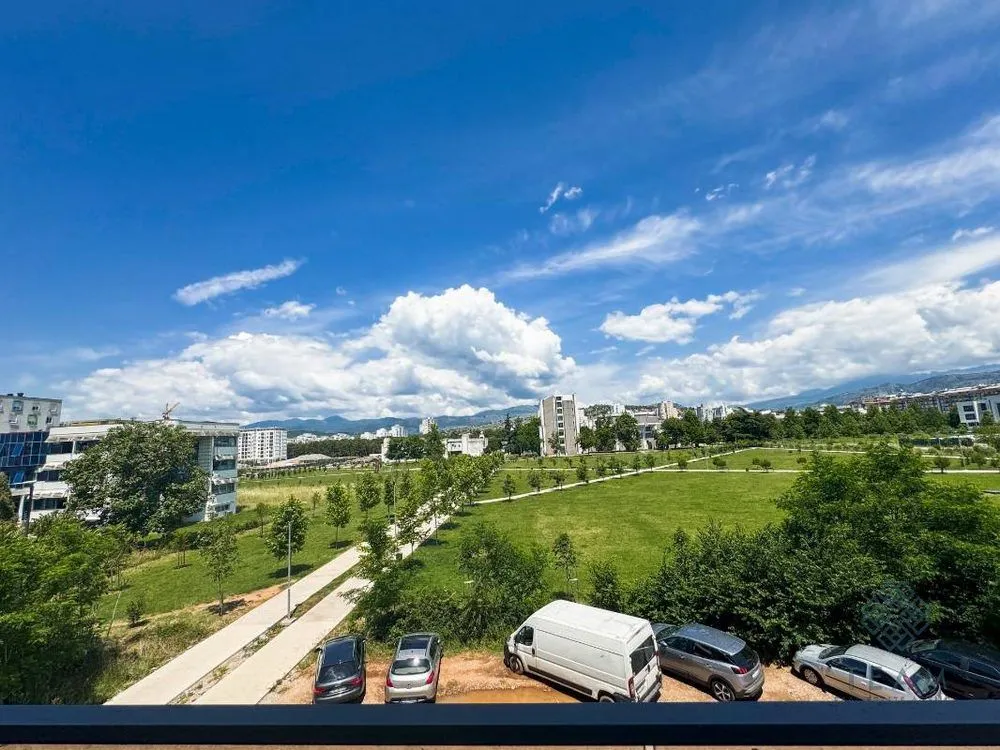 Pogled sa terase na zelenu površinu i gradski pejzaž.