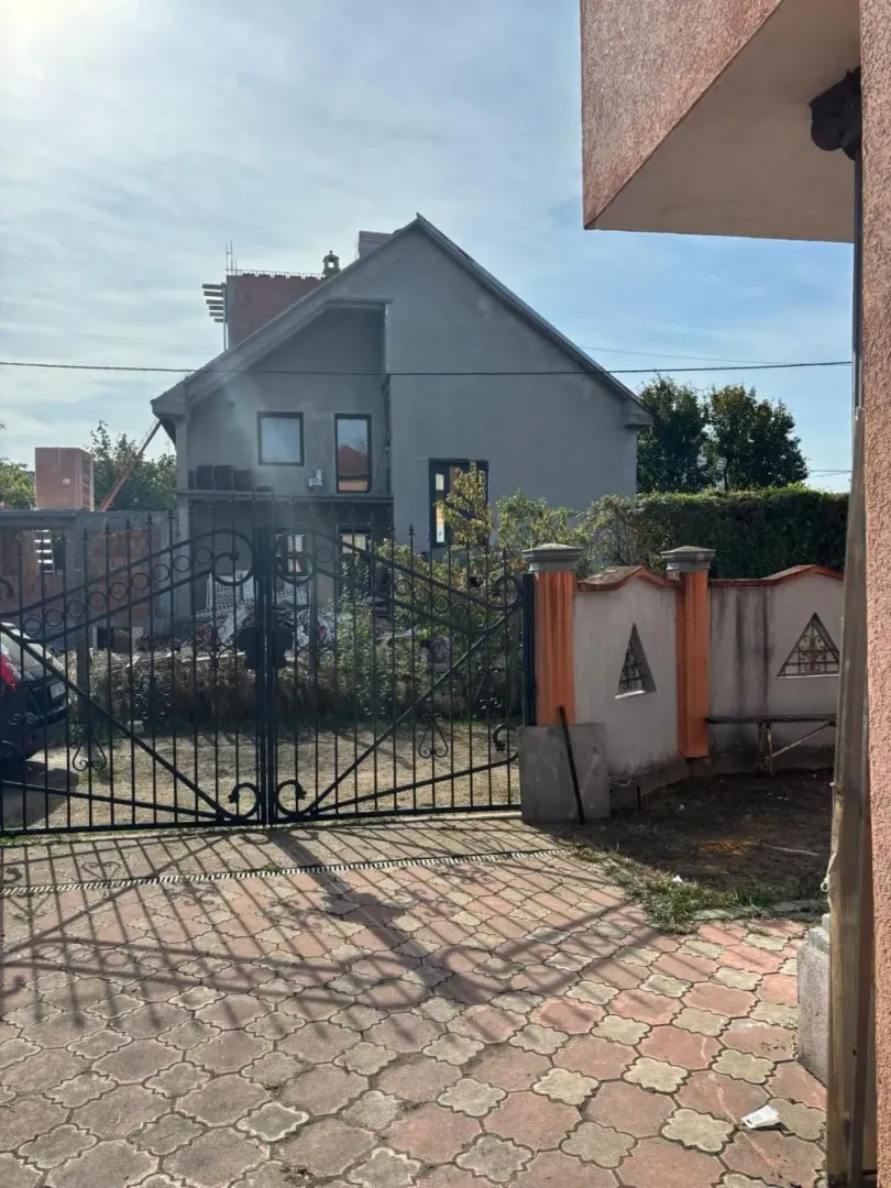 View of the courtyard and a house under construction with a wrought iron fence.