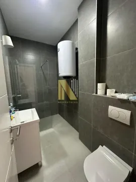 Savremeno opremljeno kupatilo sa tuš kabinom i tamnim pločicama. - image 11