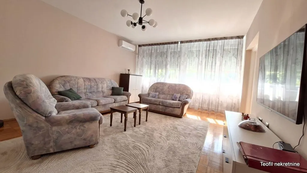 Spacious living room with seating furniture and a wall-mounted TV.