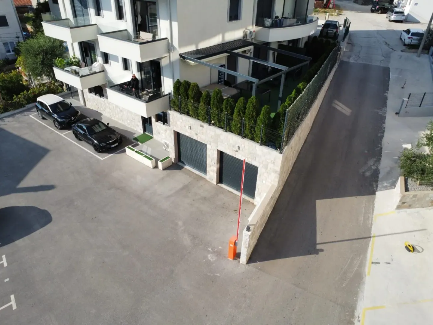Pogled iz vazduha na spoljašnjost zgrade sa parkingom i garažnim vratima.