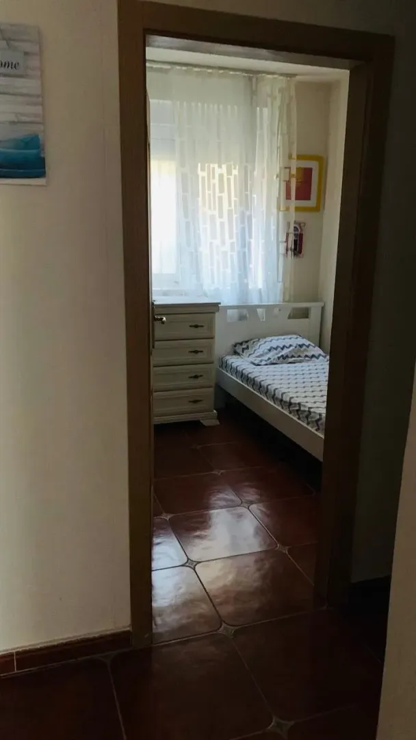 Pogled kroz vrata na urednu spavaću sobu sa krevetom i komodom.