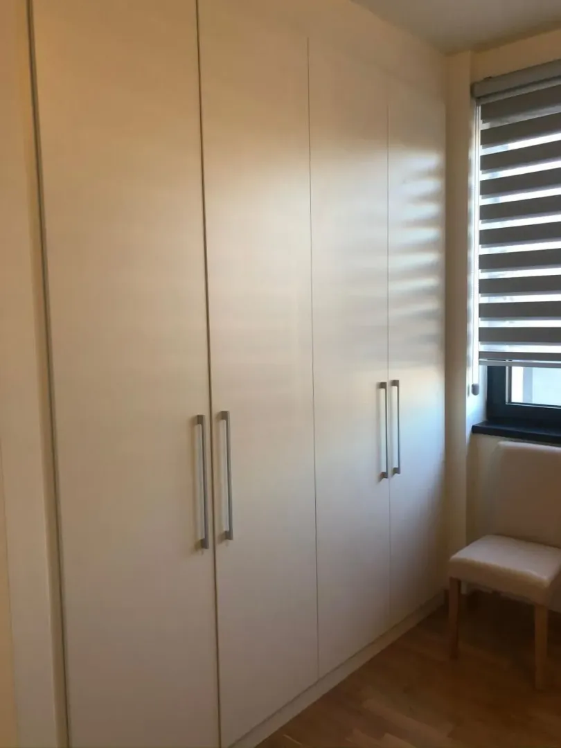 Large white built-in wardrobe in a room next to the window.