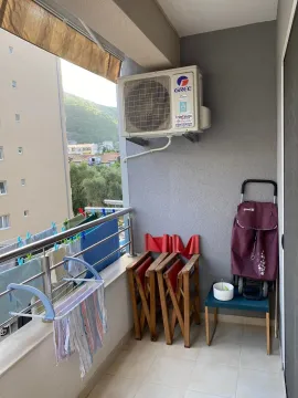 Small balcony with an air conditioning unit, folded chairs, and a clothes drying rack. - image 5