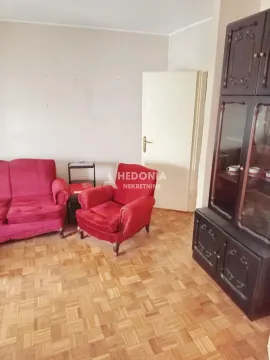 Dnevna soba sa crvenom garniturom i tamnim drvenim ormarom. - image 2