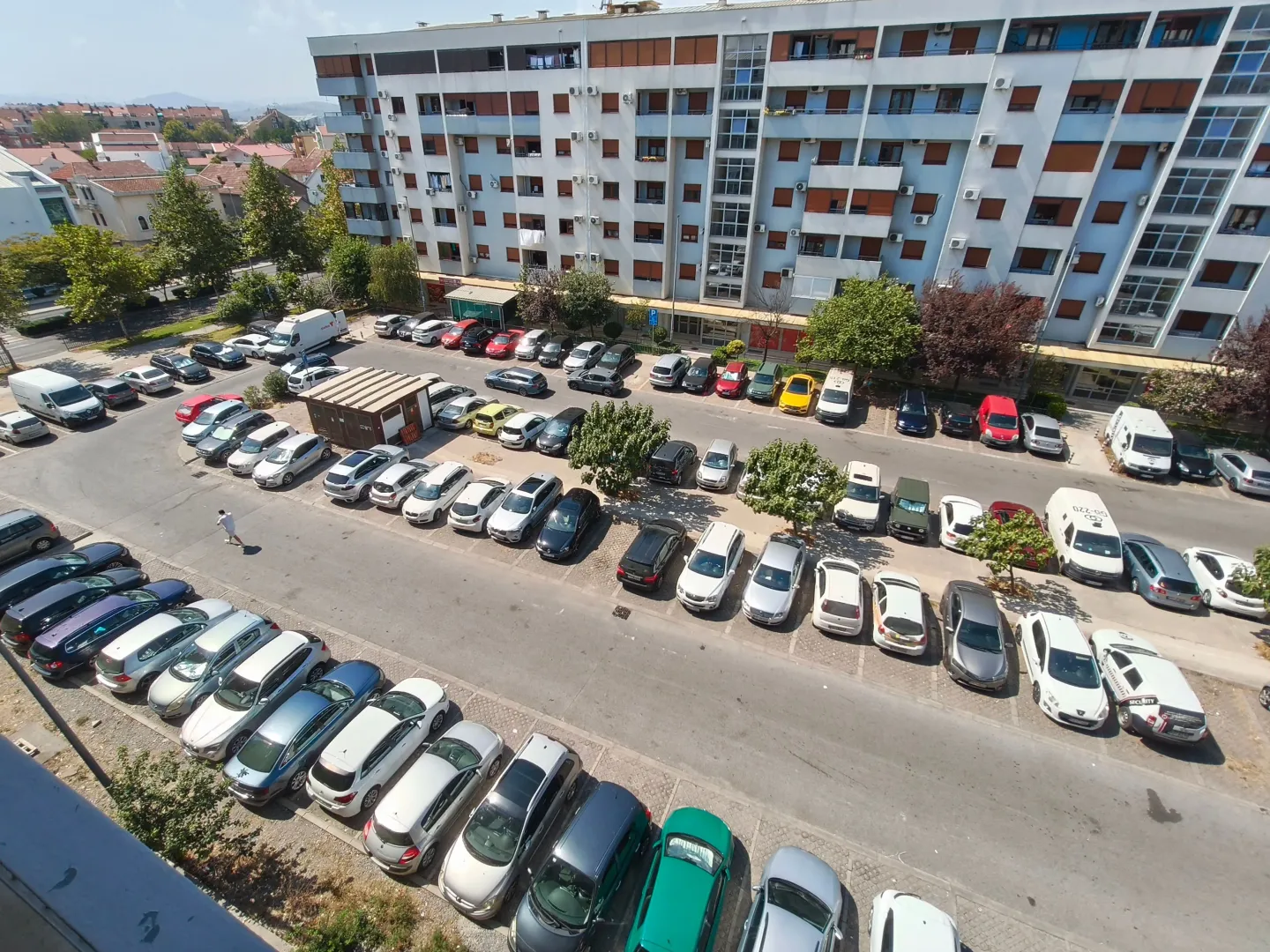 Pogled sa terase na parking i okolne zgrade.