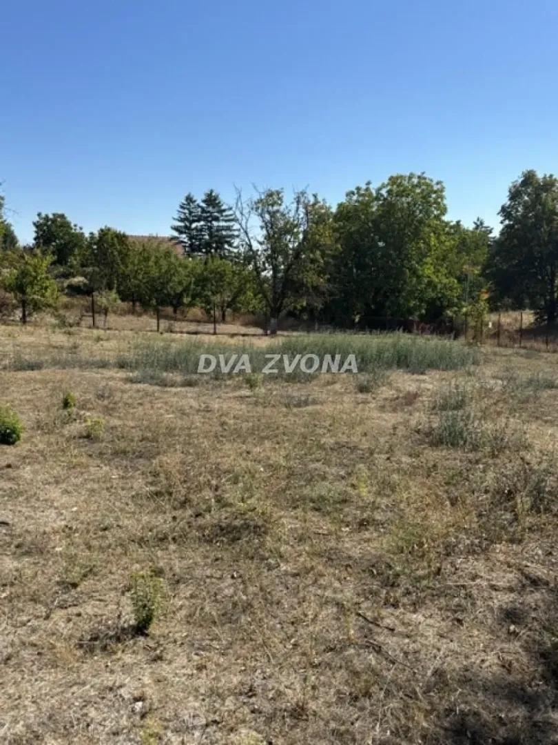 Pogled na plac sa travnatom površinom i zelenilom u pozadini.