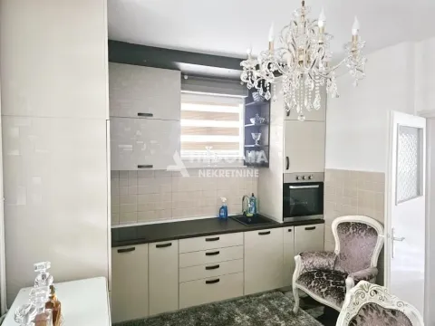 Kuhinja opremljena svetlim elementima, ugradnom rernom i kristalnim lusterom. - image 3