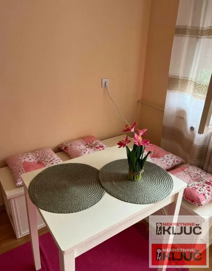 Trpezarijski sto sa klupom i jastucima u uglu sobe.