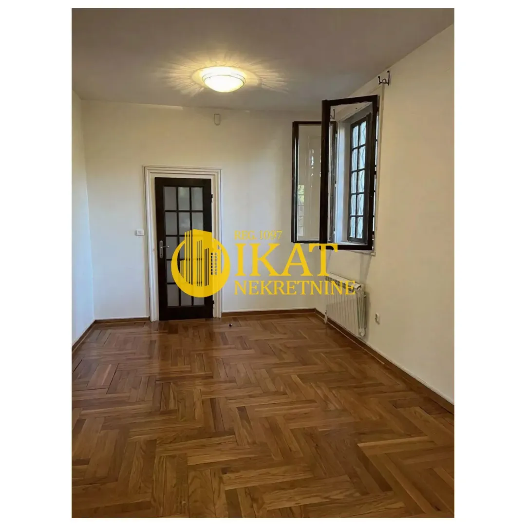 Empty room with parquet flooring, white walls and a window.