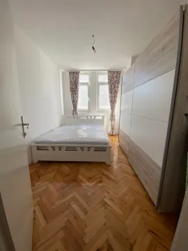 Manja spavaća soba sa bračnim krevetom, velikim ormarom i parketom na podu. - image 4