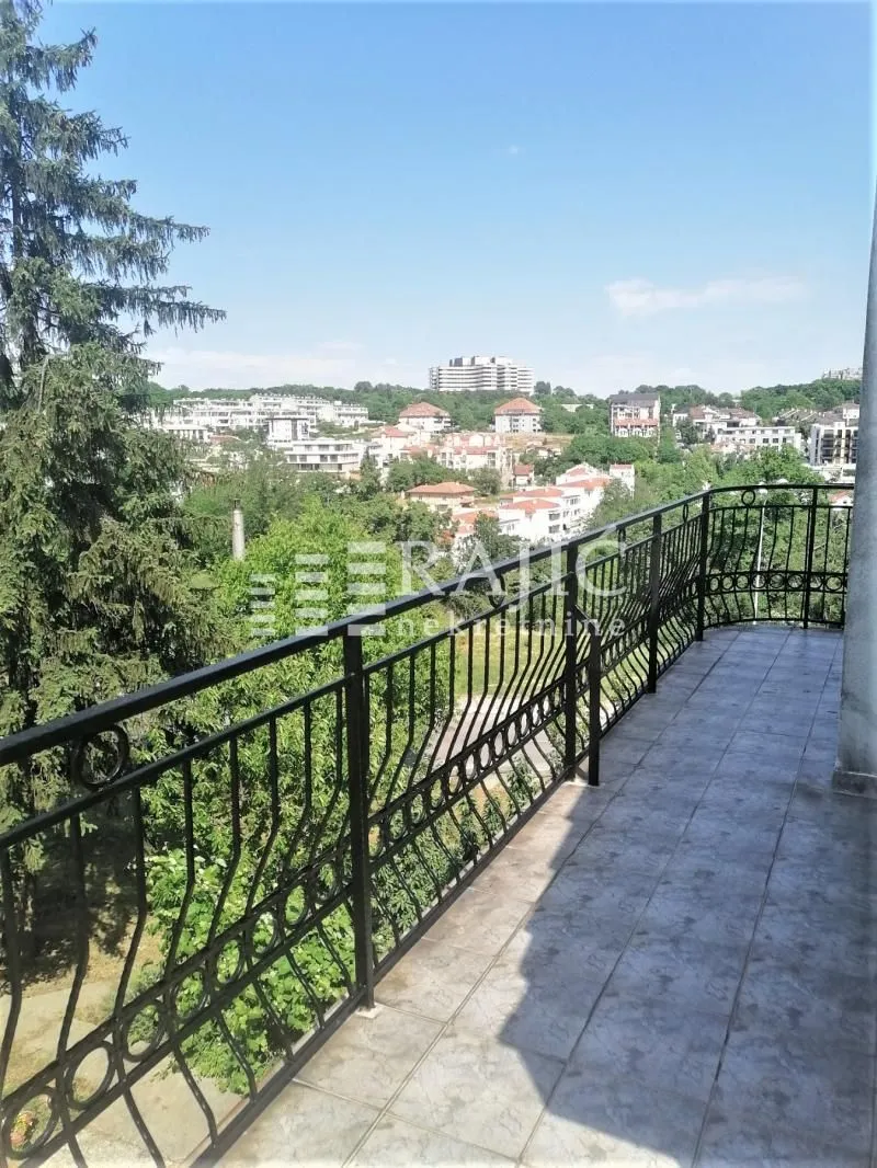 Spacious balcony with wrought iron railing and city view.