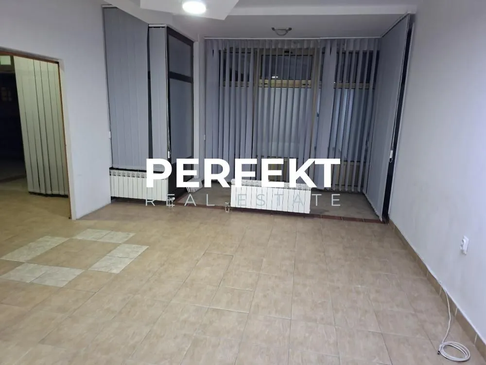 Empty room with ceramic floor tiles and large windows with blinds.