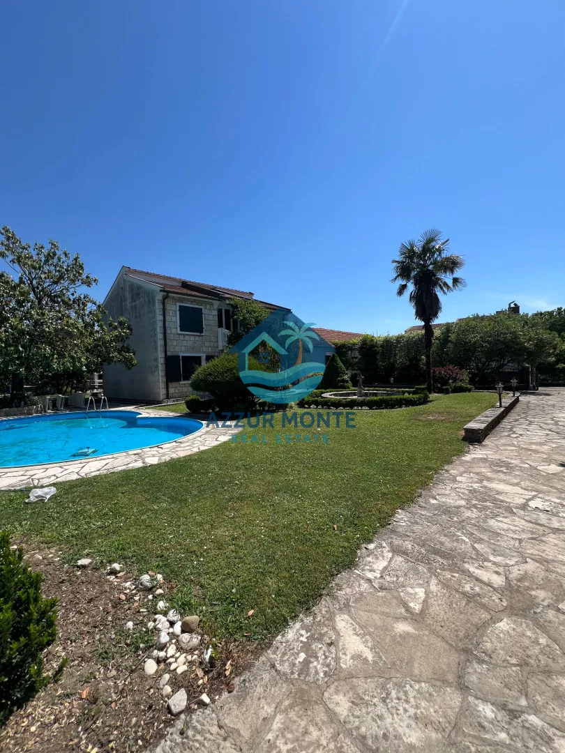 Exterior of the house with a swimming pool, landscaped yard, and a palm tree.