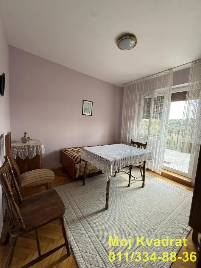 Dnevna soba sa trpezarijskim stolom, garniturom za sedenje i izlazom na terasu.