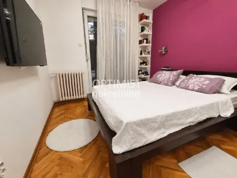 Nameštena spavaća soba sa bračnim krevetom, drvenim parketom i televizorom na zidu. - image 15