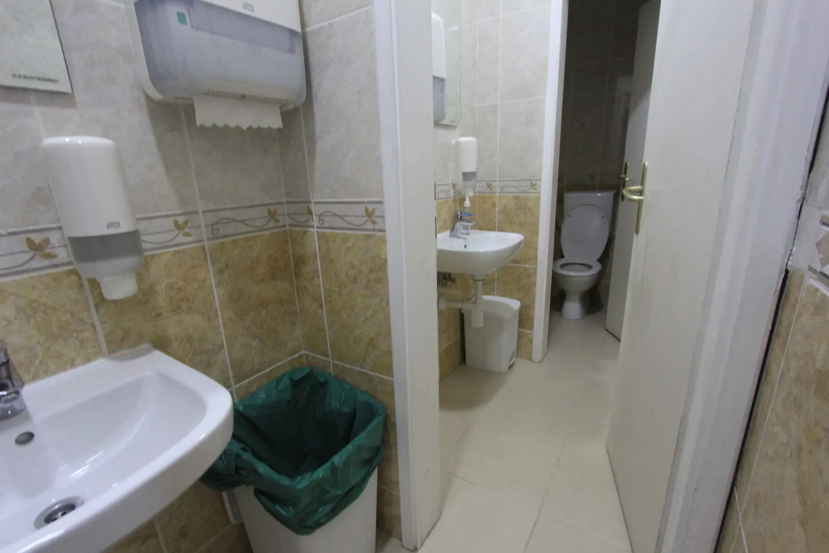 View of a bathroom with a sink and toilet in a tiled interior.