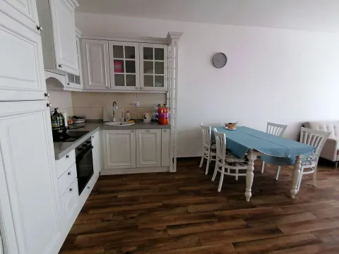 Kuhinja sa bijelim elementima i trpezarijskim stolom. - image 11