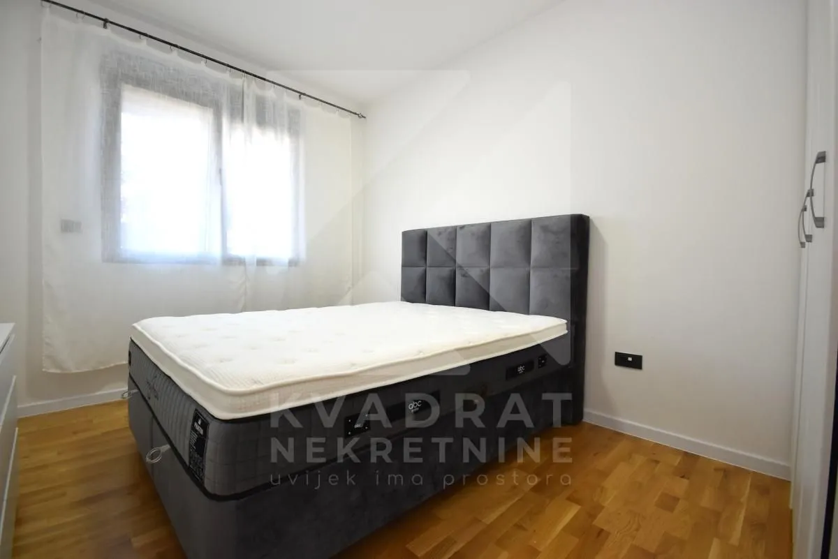 Bedroom with a double bed, white walls and wooden flooring.