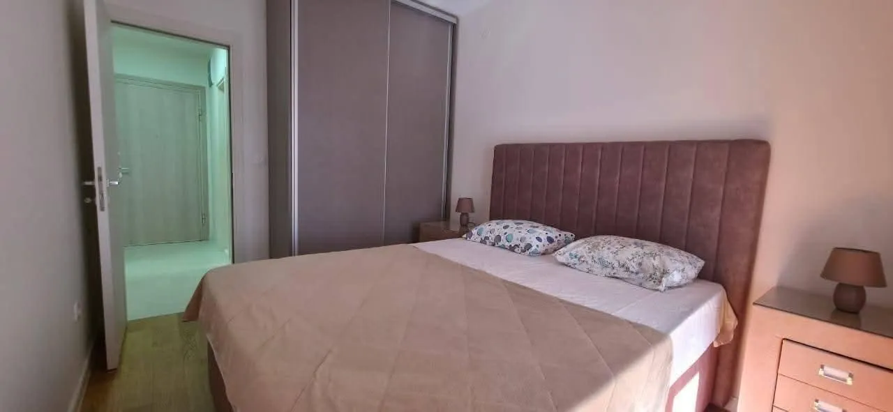 Namještena spavaća soba sa bračnim krevetom, garderoberom i noćnim stočićima.