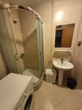Compact bathroom equipped with a shower cabin, sink, and washing machine. - image 7