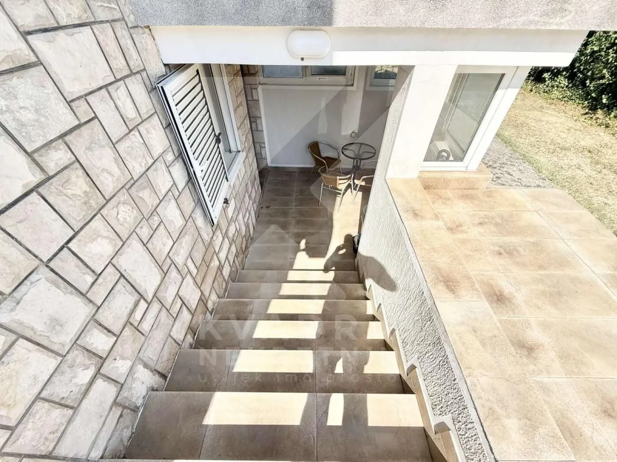 External stairs leading to the entrance of the building with a paved patio and seating set.