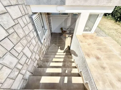External stairs leading to the entrance of the building with a paved patio and seating set. - image 10