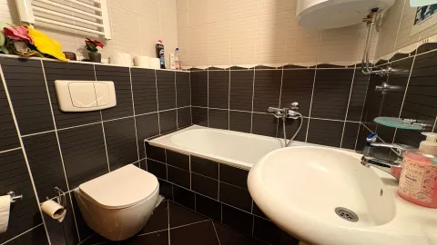 Bathroom equipped with a bathtub, washbasin, and toilet. - image 9