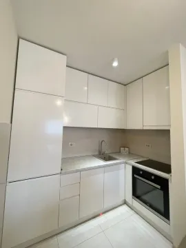 Small white kitchen with built-in appliances and a sink. - image 8