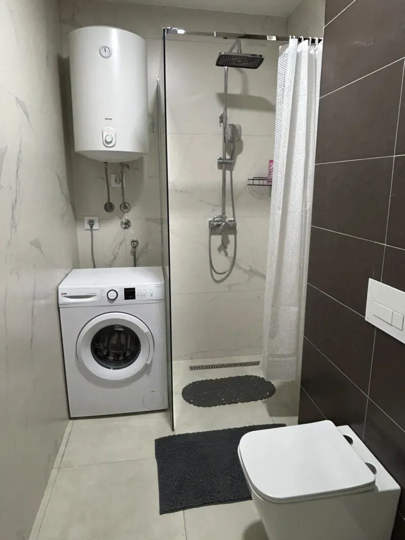 Moderno opremljeno kupatilo sa tuš kabinom, wc šoljom, bojlerom i veš mašinom.