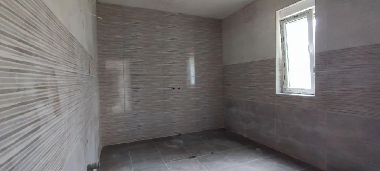 Renovated bathroom with installed tiles and a window.