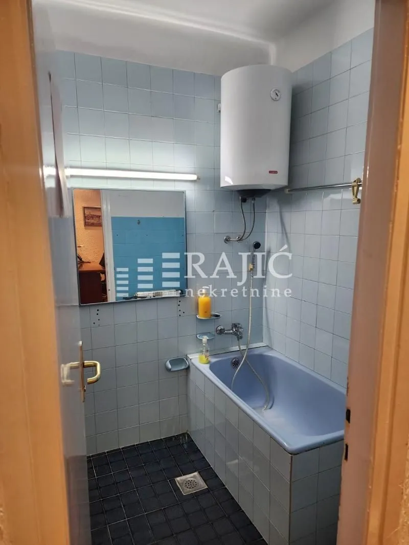 Smaller tiled bathroom with a bathtub and water heater.