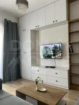 Dnevna soba sa bijelim ormarima, TV-om i drvenim stočićem. - image 3