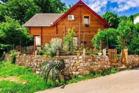 Exterior of a traditional wooden house with a stone wall and a landscaped yard. - image 11
