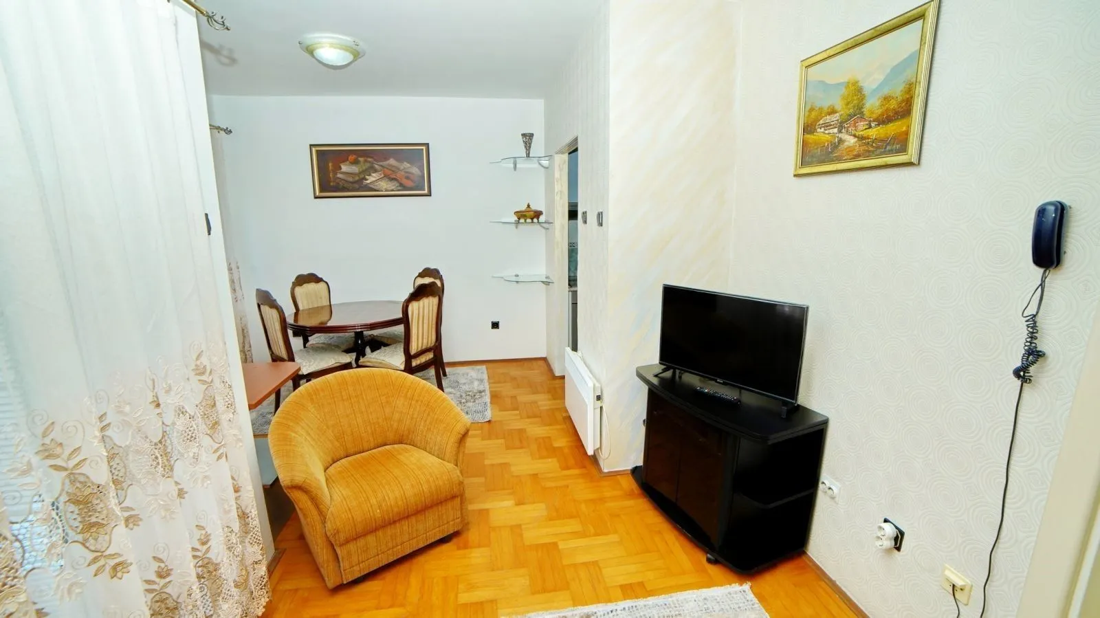 Living room with a yellow armchair, television, and dining table.