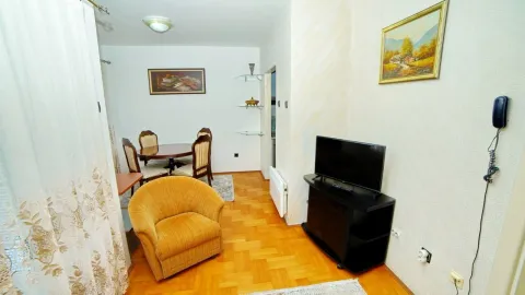 Living room with a yellow armchair, television, and dining table. - image 13