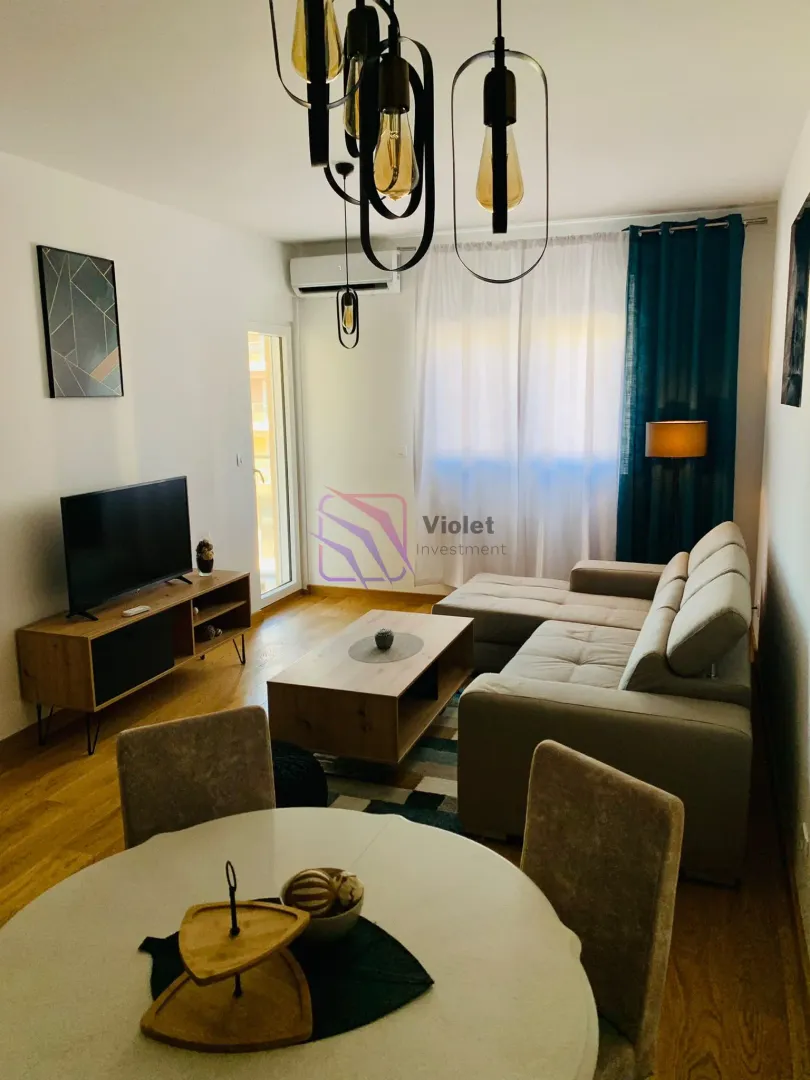 Living room with sofa, TV and dining table.