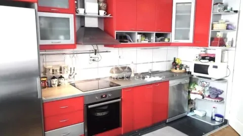 Modern kitchen with red cabinets and built-in appliances. - image 6