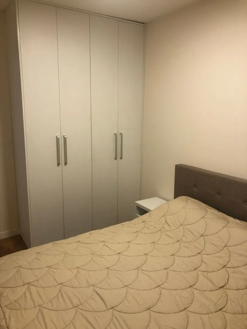 Namještena spavaća soba sa bračnim krevetom i ugradnim plakarom.
