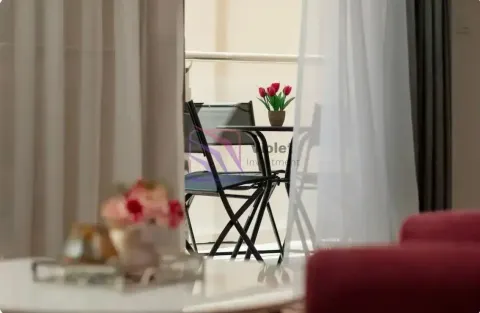 Pogled kroz zavjese na namješteni balkonski prostor sa stolom i stolicama. - image 6