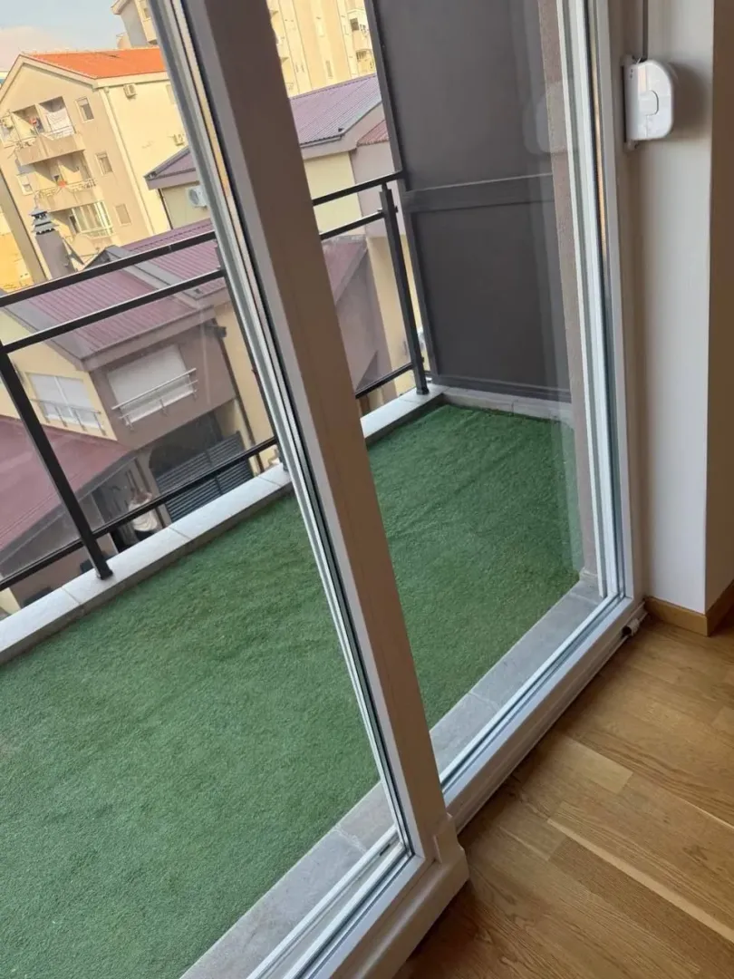 View of the balcony with artificial grass through the balcony doors.
