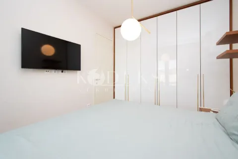 Moderna spavaća soba sa bračnim krevetom, ugradnim ormarom i televizorom na zidu. - image 6