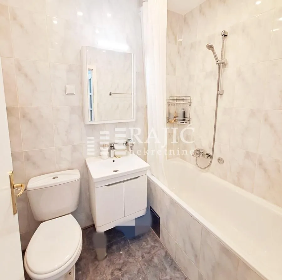 Compact bathroom with a bathtub, washbasin, and toilet.