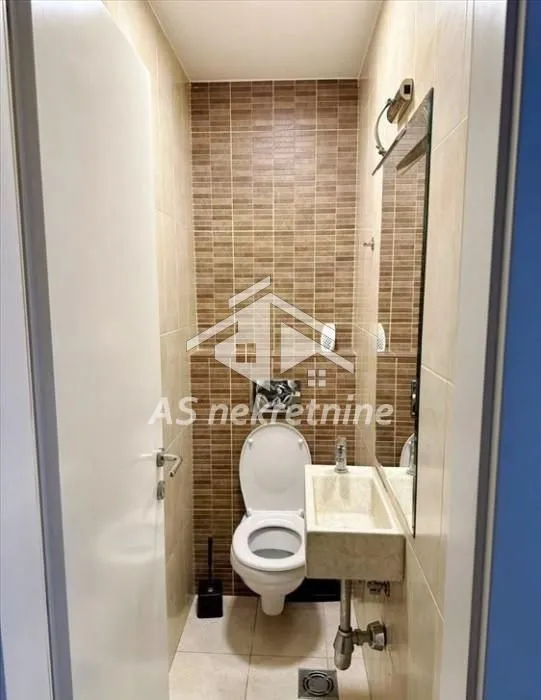 Manje kupatilo sa WC šoljom, umivaonikom i ogledalom.