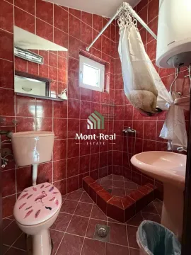 Kupatilo obloženo crvenim pločicama sa wc šoljom, lavaboom i tuš kabinom. - image 13