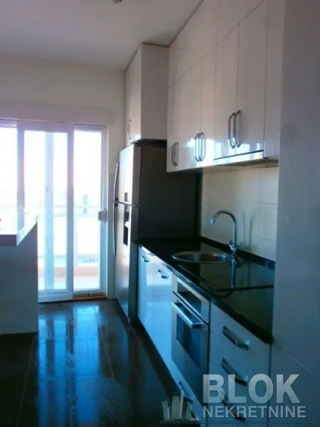 Kitchen equipped with white cabinetry, dark countertops, and built-in appliances.