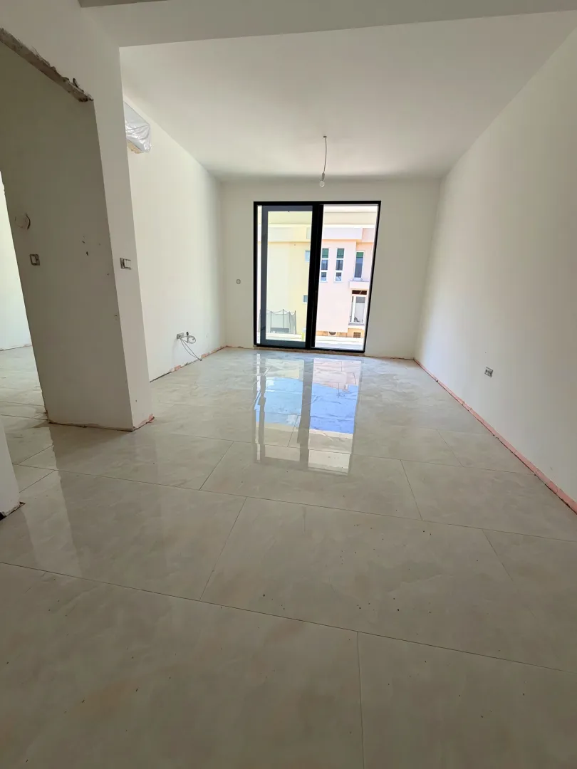 Empty bright room with ceramic floor tiles and balcony doors.