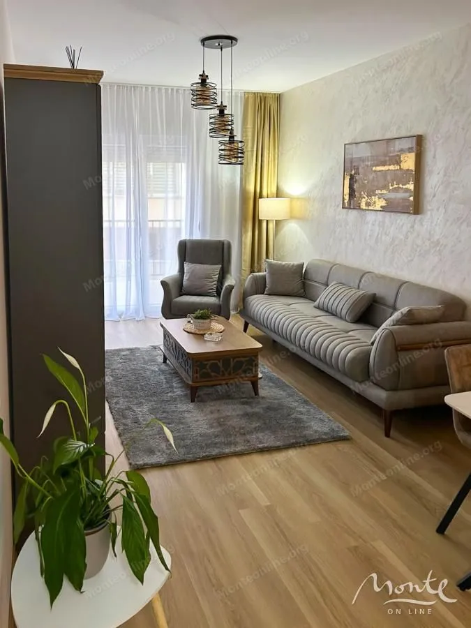 Udobna dnevna soba sa garniturom za sjedenje, foteljom i modernim lusterom.